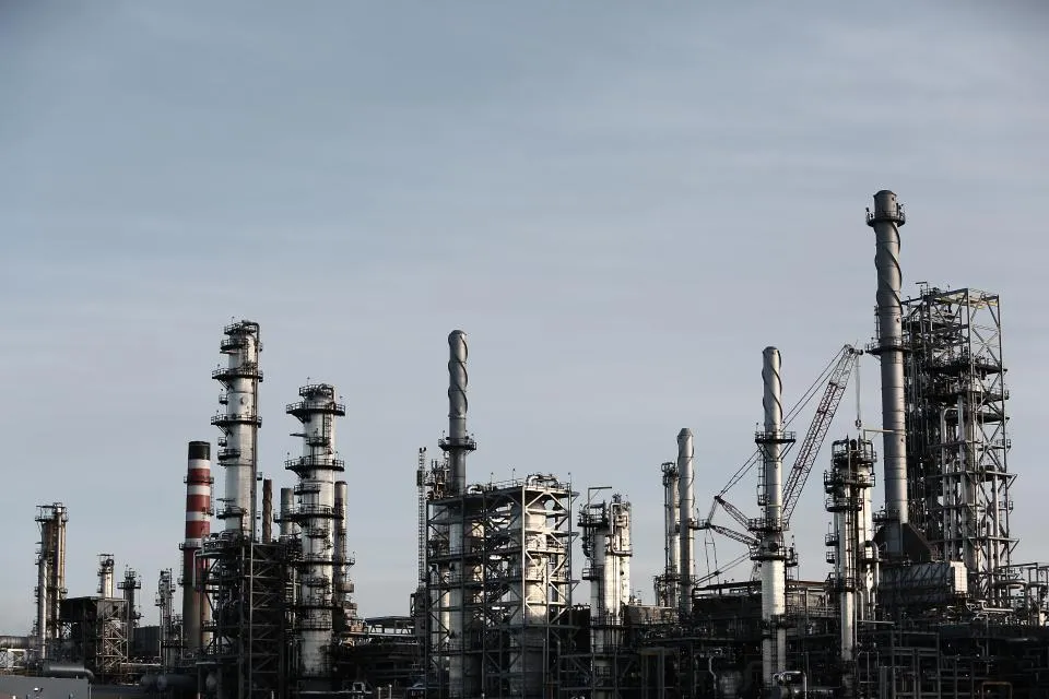Processing towers and pipework of an industrial plant under a grey sky